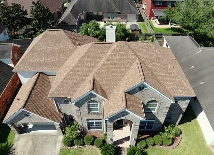 Completed brown asphalt shingle roof on a two-story brick home