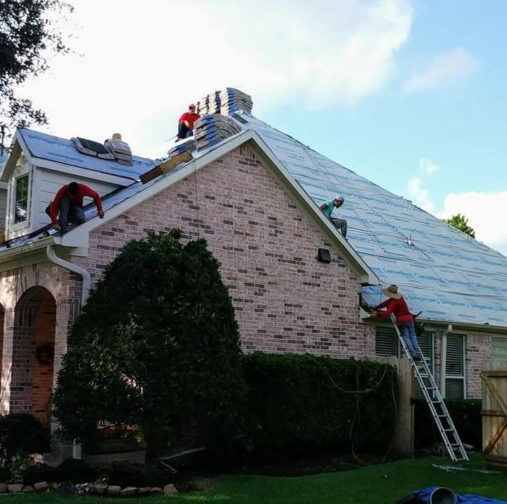 Roofing crew installing underlayment and flashing around a chimney