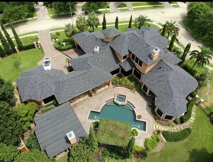 Completed gray shingle roof on a large estate home with circular driveway