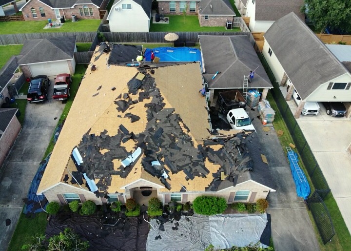 Aerial view of storm-damaged shingles torn off a roof deck