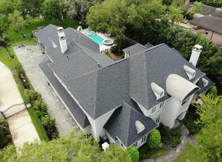 Completed dark gray shingle roof on a large estate home with pool